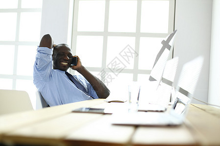 在笔记本电脑上工作的戴耳机的非裔美国商务人士经理人士沉思桌子审查办公室商务文档血统文书图片
