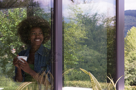 喝咖啡的非裔美国妇女向窗外看望着咖啡奢华女士咖啡店公寓杯子头发女性窗户微笑快乐图片