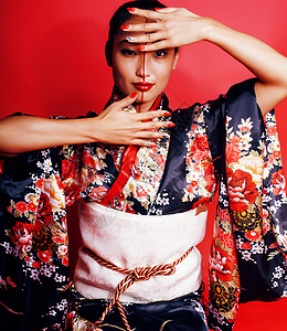 日本化妆品红背景的年轻漂亮的艺妓 在东方和服中出现传统女士白色戏服文化红色化妆品情调头发异国背景