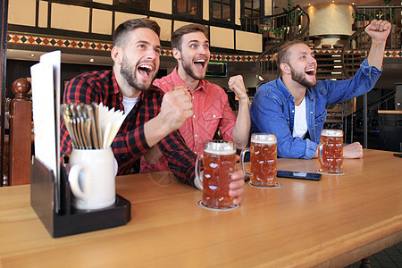在酒吧看橄榄球 朋友们喝啤酒快乐 为最喜爱的队伍欢呼 庆祝胜利吧 掌声垃圾会议队友手表乐趣微笑运动草稿电视学士图片