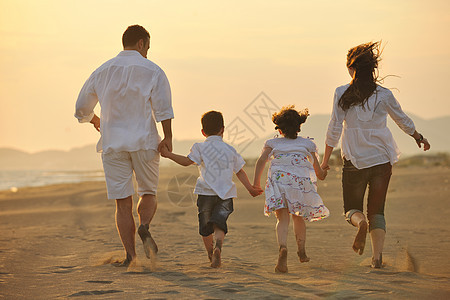 快乐的年轻家庭 在日落时在海滩上玩得开心天空微笑海洋女性妈妈孩子喜悦女儿旅行成人图片