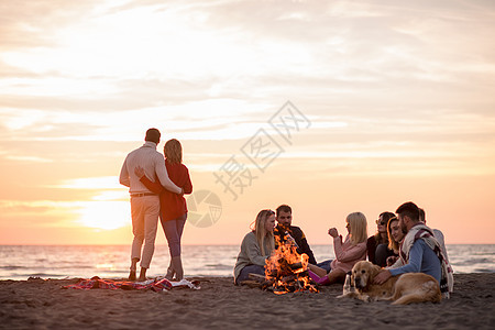 在海滩日落时和朋友共度欢乐的情侣友谊营火幸福乐趣火焰休闲啤酒动作夫妻男人图片