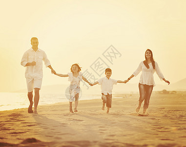 快乐的年轻家庭 在日落时在海滩上玩得开心男性海洋童年生活太阳微笑孩子们天空母亲成人图片