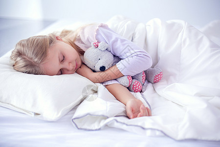 小女孩睡在床上 跟玩具泰迪熊睡觉童年女孩毯子寝具卧室女性就寝时间孩子枕头图片