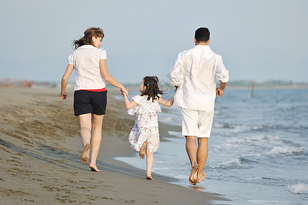 快乐的年轻家庭在海滩上玩得开心天空活动儿子女性支撑海洋女儿童年乐趣喜悦图片
