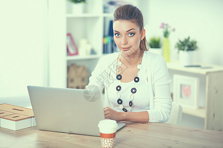 一名商业妇女用笔记本电脑坐在办公桌上的肖像办公室技术珠子键盘人士服务顾客工作女性成人图片