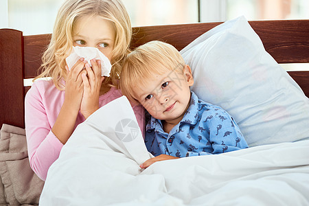 只是休息和睡觉 在家里一起躺在床上流鼻涕的小妹妹和弟弟患有流感或感冒 病毒病图片