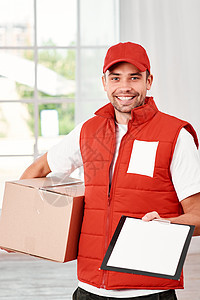 满意的客户是广告的最佳来源 一位快乐的年轻送货员在室内用包裹箱站着的照片 (笑声)图片