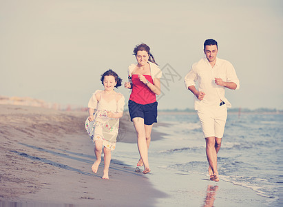 快乐的年轻家庭在海滩上玩得开心男人儿子闲暇微笑支撑童年天空乐趣女孩喜悦图片