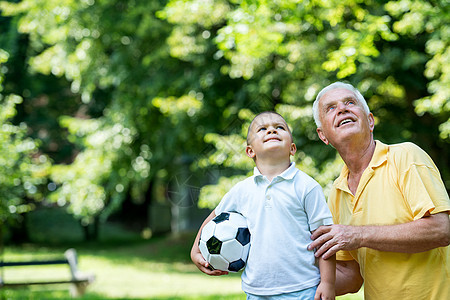 爷爷和孩子在公园玩得开心祖父母男性儿子微笑祖父自行车喜悦学习孙子足球图片
