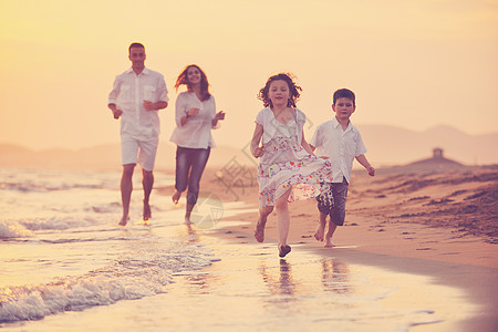 快乐的年轻家庭 在日落时在海滩上玩得开心妈妈太阳儿子童年父母男生孩子热带天空父亲图片