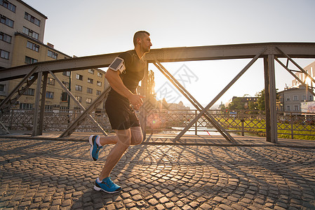 在阳光明媚的清晨 一个人在桥对面慢跑城市跑步男人男性慢跑者锻炼街道晴天享受活动背景图片