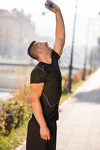 人从瓶子中倒水在他的头上训练男性男人运动装晴天活力身体城市娱乐茶点图片