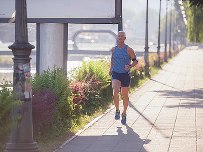 英俊的高级男子慢跑街道城市男人耀斑训练活动阳光运动员身体男性图片