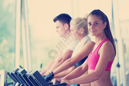 朋友们在明亮现代体育馆的跑步机上运动黑发微笑跑步重量有氧运动男人运动装模拟器机器女士图片