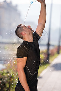 人从瓶子中倒水在他的头上男人运动装茶点训练娱乐赛跑者身体晴天活动男性图片