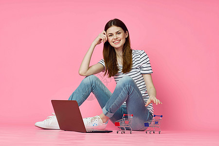 妇女用笔记本电脑坐在地面技术网上购物粉色背景的互联网上办公室银行业店铺网络女性信用白色卡片电子商务商业图片