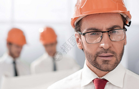 以模糊的背景来描绘充满自信的建筑设计师安全帽建筑男人商务人士团体男性商业工程师蓝图图片