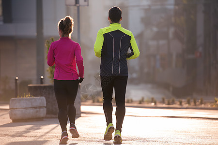 年轻夫妇慢跑公园闲暇城市太阳女士跑步者男人训练卷曲耀斑图片