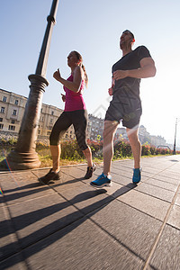 年轻夫妇在城里慢跑街道运动员家庭跑步女孩训练活动运动装晴天慢跑者图片