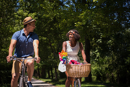 具有自然骑自行车的多种族年轻夫妇活动朋友们男性娱乐成人公园天空运动闲暇女士图片