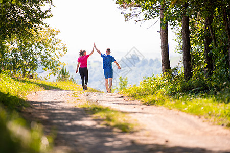 在阳光明媚的自然日子里 玩慢跑的情侣互相击掌日落女孩太阳跑步赛跑者女士夫妻森林女性练习图片