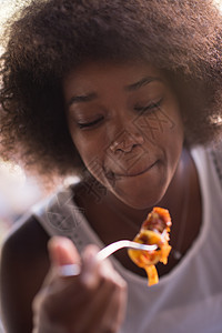 一位年轻的非裔美国女人 吃意大利面粉烹饪香菜玻璃饮食文化午餐植物火鸡女士蔬菜图片