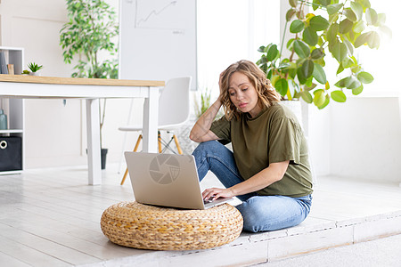 妇女使用膝上型计算机 坐在家庭内地的地板上工作笔记本学生客厅情感植物女士电脑桌子业者图片