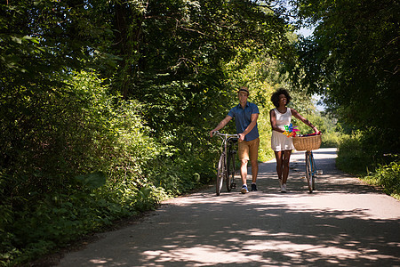具有自然骑自行车的多种族年轻夫妇男性公园成人活动运动朋友们闲暇女性女士农村图片