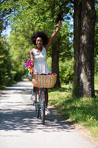 在森林里骑自行车的 年轻漂亮的非洲裔美国女人公园女性成人牛仔裤闲暇乐趣微笑爆炸享受晴天图片