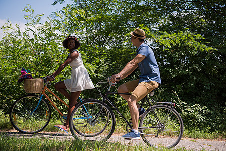 具有自然骑自行车的多种族年轻夫妇闲暇农村成人森林男性男人运动骑术活动乐趣图片