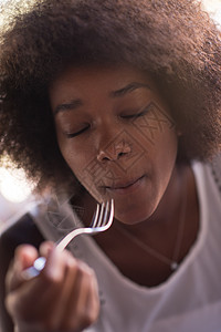 一位年轻的非裔美国女人 吃意大利面粉面条桌子午餐玻璃食物蔬菜火鸡盘子香菜女士图片