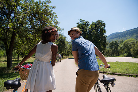 具有自然骑自行车的多种族年轻夫妇天空女性农村运动公园男人森林男生成人活动图片
