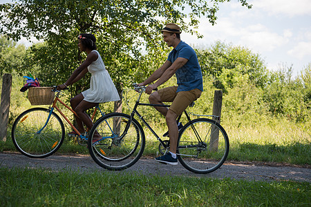 具有自然骑自行车的多种族年轻夫妇男生运动成人森林天空公园骑术活动娱乐城市图片
