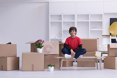 男孩坐在桌子上 他周围有纸板盒纸板房子家庭解决方案公寓开箱纸盒搬迁房间乐趣图片
