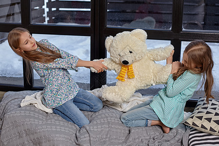 两个可爱的小妹妹 为一只大玩具熊而战的模样玩具家具朋友金发窗台游戏情感孩子女孩房间图片