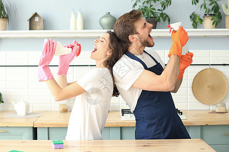 年轻快乐的情侣在家打扫和唱歌时玩得很开心手套女孩厨房微笑男人家庭工作妻子卫生成人图片