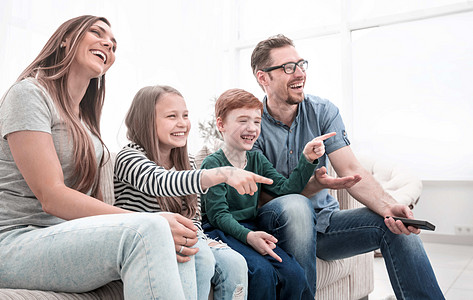 快乐的家庭在看他们最喜欢的电视节目程序沙发享受儿子休息室父亲女儿公寓女士男性图片