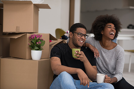 非裔美国人夫妇在新房子里放松搬迁地面开箱杯子纸板盒子财产家庭房间包装图片