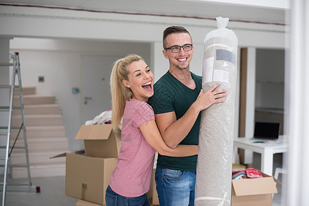 一对夫妇携带地毯搬进新家开箱客厅包装搬迁财产男人家庭幸福妻子微笑图片