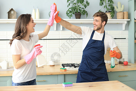 快乐的年轻夫妇在家打扫时玩得很开心家庭成人卫生女孩洗涤剂工作男性抹布微笑帮助图片