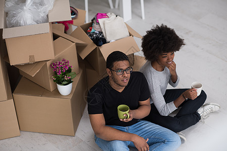 非裔美国人夫妇在新房子里放松财产地面房间女士已婚杯子开箱包装微笑盒子图片
