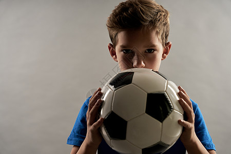 可爱的男孩用足球球蒙住嘴图片