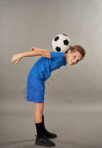 脸背带着足球球的可爱男孩 在灰色背景下站立图片