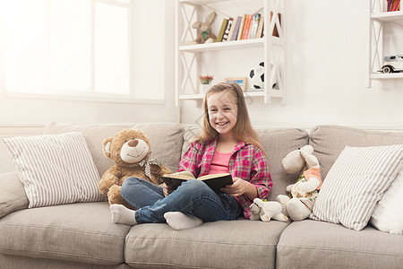 快乐的小孩 为她的泰迪熊读书游戏婴儿教育拥抱闲暇玩具房间长椅女孩孩子图片
