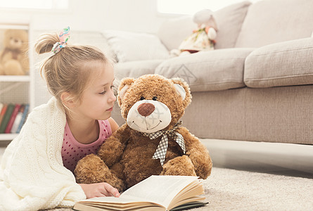 快乐的小女孩和她的泰迪熊看书拥抱闲暇喜悦婴儿乐趣房间孩子教育说谎幸福图片