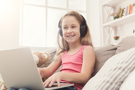 小女孩在家用笔记本电脑做家庭作业技术乐趣女孩孩子教育音乐学习互联网家庭作业键盘图片