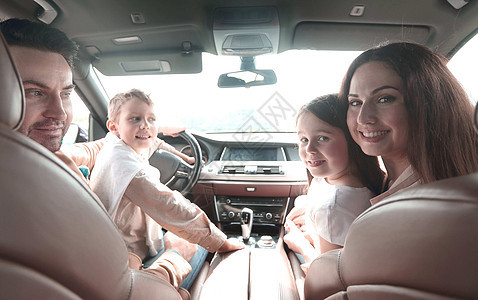 坐在车里的幸福家庭坐着母亲运输闲暇微笑爸爸女性儿子男性汽车女士图片