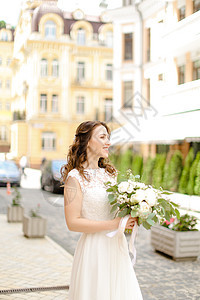 白种人迷人的新娘在城市里带着花束走来走去图片