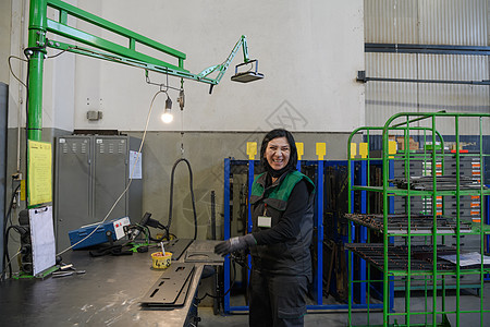 在现代金属生产和加工行业工作的一名妇女焊接产品并为数控机床做准备工业工具职业作坊工厂商业女性车库男人工人图片